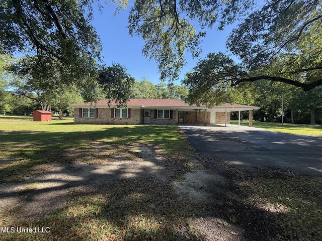 6709 Caraway Rd, Moss Point, MS 39562 - ranch-style house featuring a carport, aphalt driveway, a front lawn, a shed, and an outbuilding