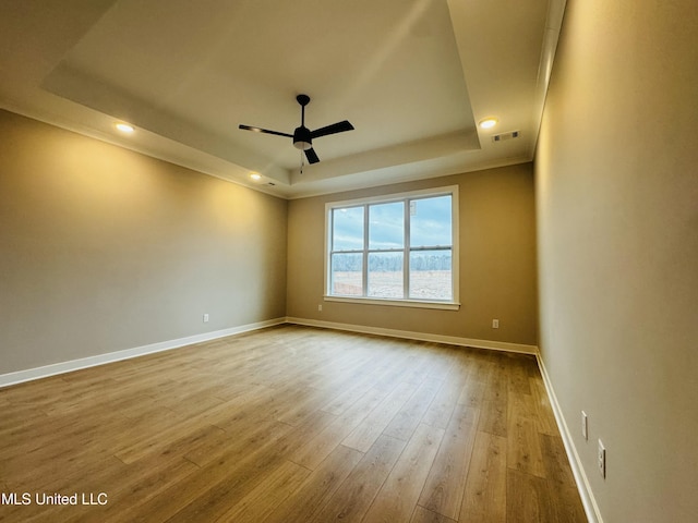 spare room featuring wood-type flooring, a raised ceiling, and ceiling fan