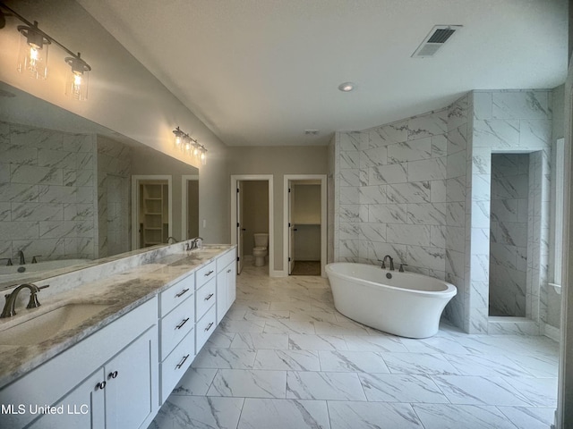 5322 Grays Valley Dr, Hernando, MS 38632 - bathroom with marble look tiles, a freestanding bath, tile walls, double vanity, and recessed lighting
