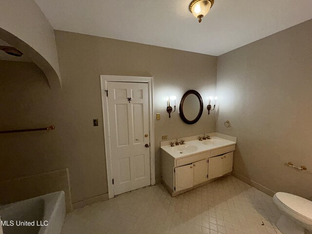 341 N Ruby Ave, Ruleville, MS 38771 - bathroom featuring double vanity, toilet, baseboards, and a sink