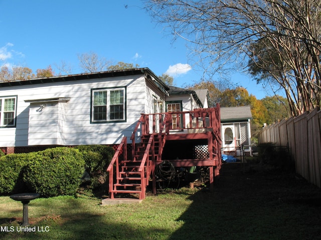 rear view of house with a lawn and a wooden deck