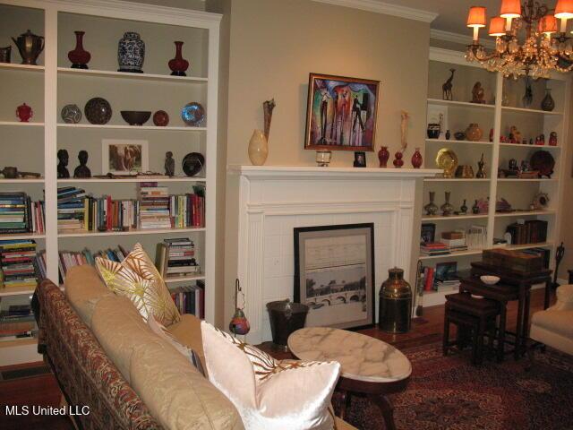 sitting room featuring a fireplace, ornamental molding, a chandelier, and wood-type flooring