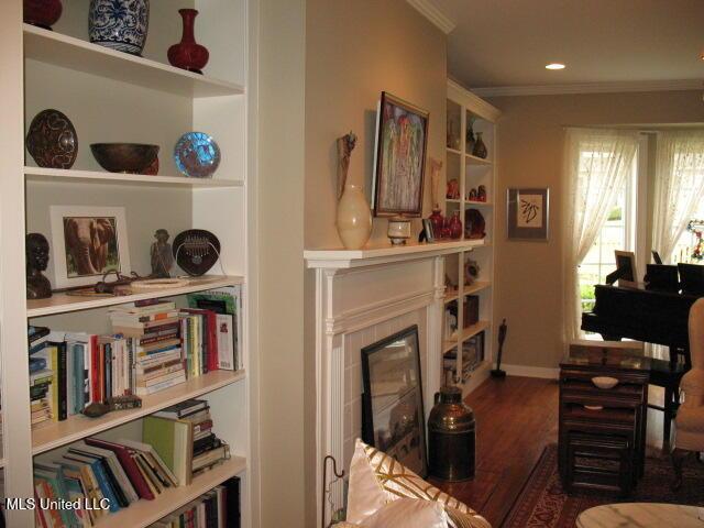 living area with a fireplace, hardwood / wood-style floors, and ornamental molding