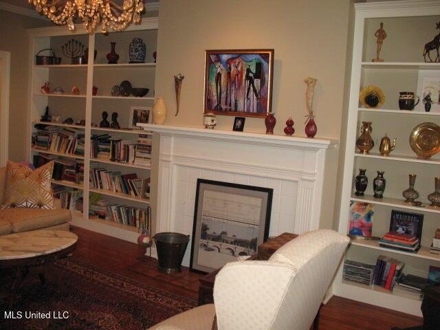 living area with dark hardwood / wood-style flooring, crown molding, a tile fireplace, and an inviting chandelier