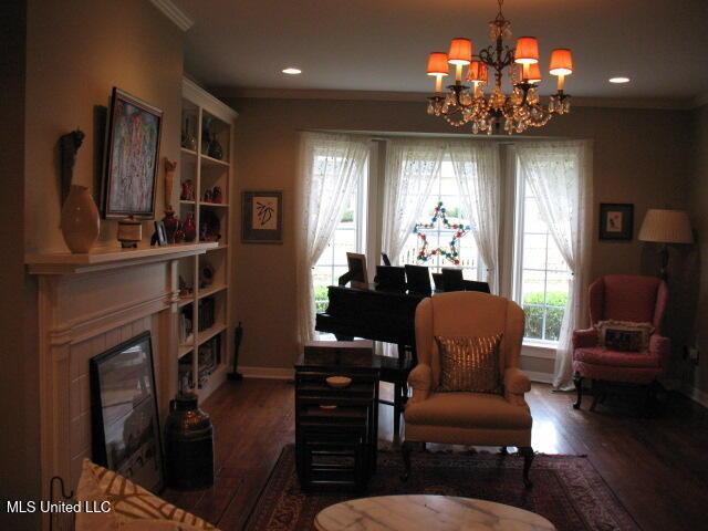 living area featuring crown molding, dark hardwood / wood-style floors, and a notable chandelier