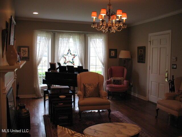 living area with ornamental molding, plenty of natural light, wood-type flooring, and an inviting chandelier