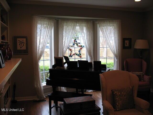 living area featuring a wealth of natural light, hardwood / wood-style floors, and ornamental molding