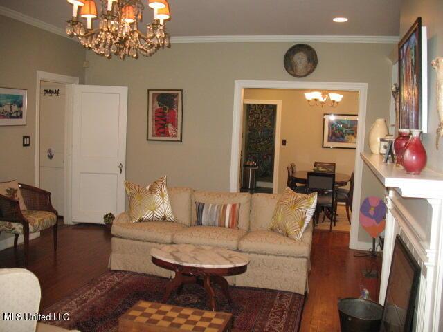 living room with a notable chandelier, dark hardwood / wood-style floors, and ornamental molding