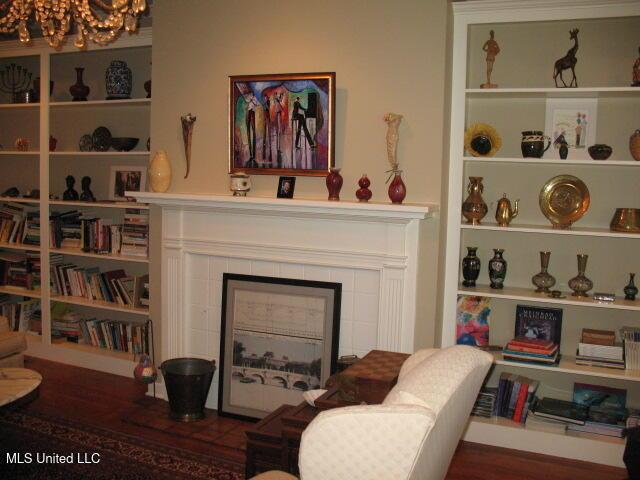 living area with wood-type flooring, a tile fireplace, and an inviting chandelier