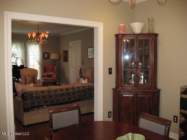 dining room featuring dark hardwood / wood-style flooring, an inviting chandelier, and ornamental molding