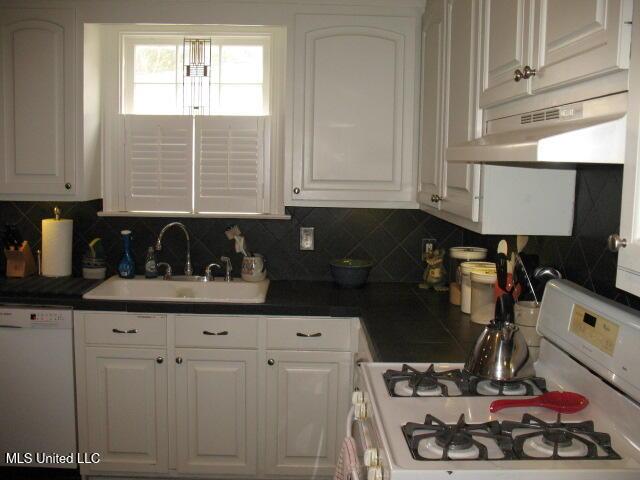 kitchen with backsplash, sink, white cabinets, and white appliances