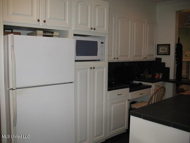 kitchen with decorative backsplash, tile counters, white cabinets, and white appliances