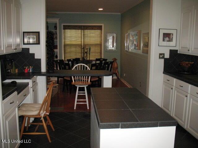 kitchen with white cabinets, decorative backsplash, and a kitchen island