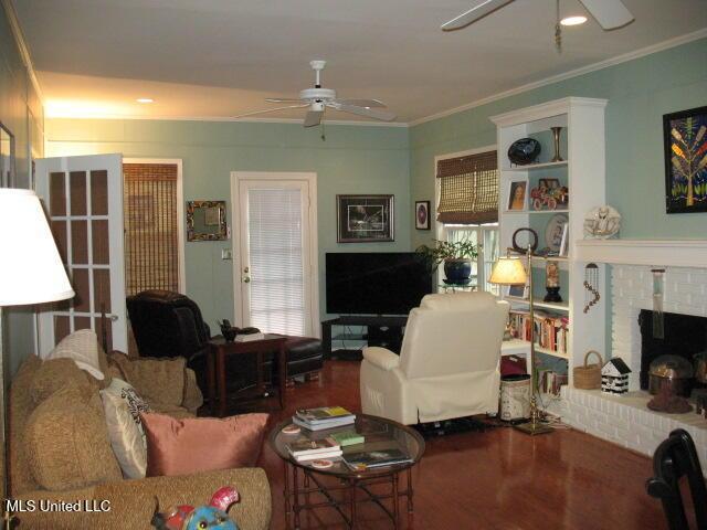 living room featuring hardwood / wood-style floors, ceiling fan, ornamental molding, and a fireplace