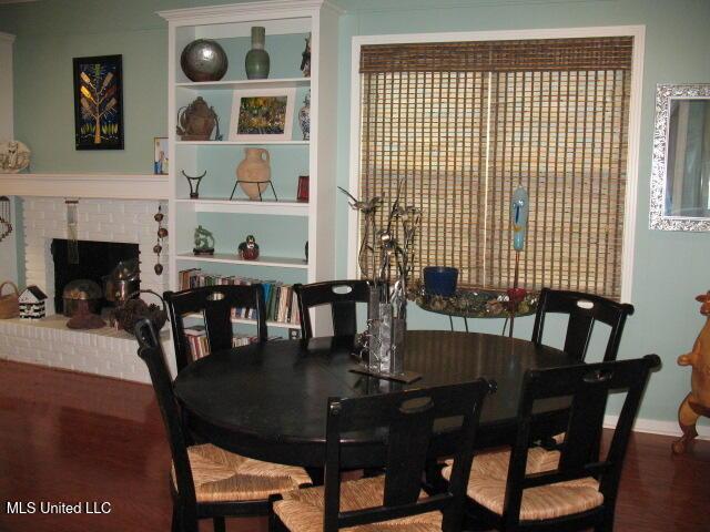 dining area with hardwood / wood-style floors, built in features, and a brick fireplace