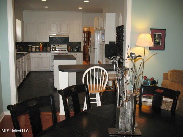 kitchen featuring sink, white appliances, white cabinetry, and backsplash