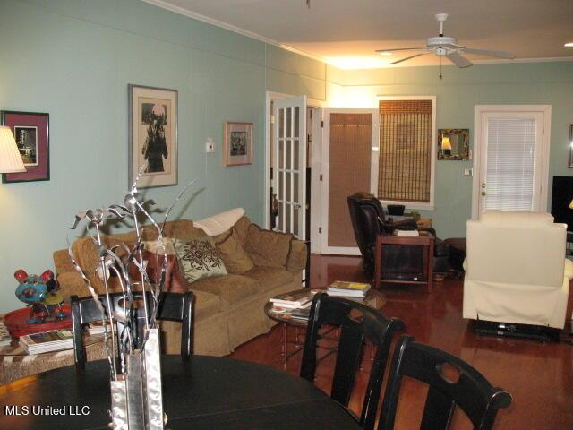 living room featuring ceiling fan, crown molding, and dark wood-type flooring