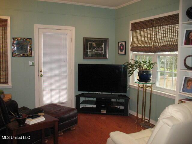 living room featuring wood-type flooring and crown molding