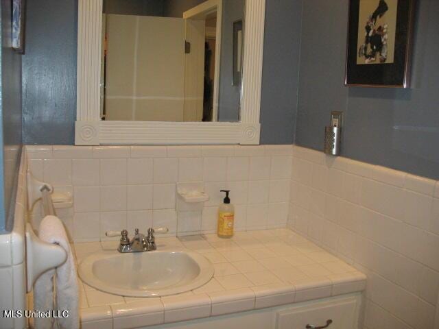 bathroom featuring vanity and tile walls