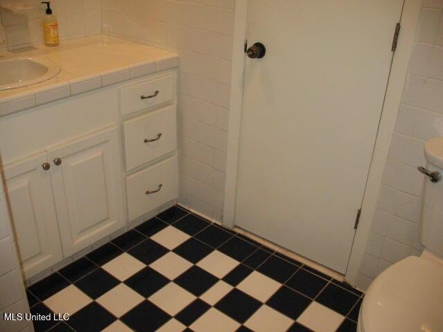 bathroom featuring vanity, toilet, and tile walls