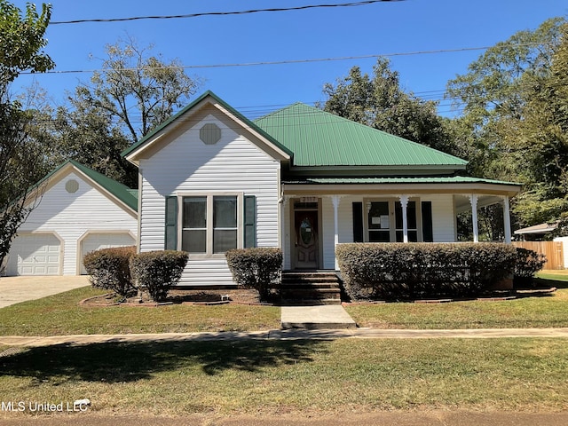 view of front of property with covered porch, a garage, a front lawn, and an outdoor structure