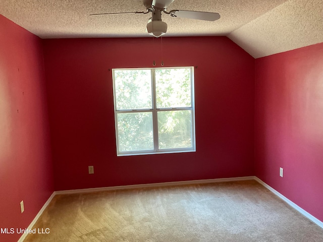 carpeted empty room featuring ceiling fan, lofted ceiling, and a textured ceiling