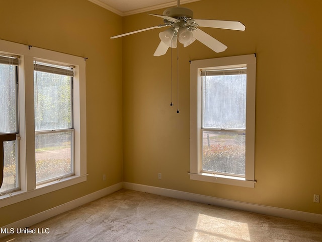 carpeted spare room featuring plenty of natural light, ceiling fan, and crown molding