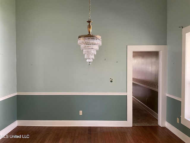 spare room featuring a chandelier and dark hardwood / wood-style flooring