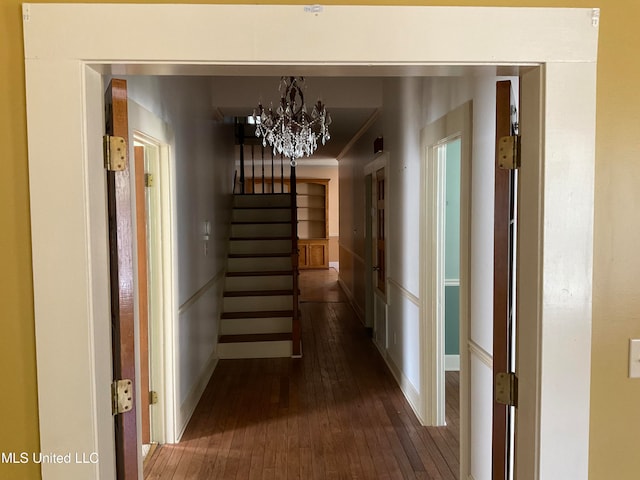 hall featuring dark wood-type flooring and a notable chandelier