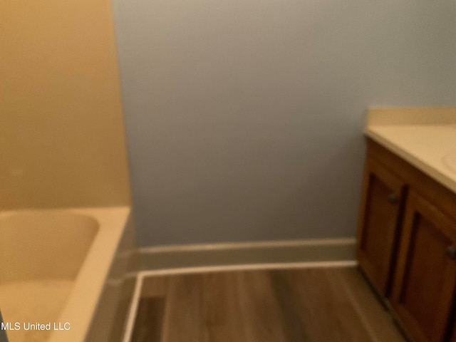 bathroom with a washtub, hardwood / wood-style floors, and vanity