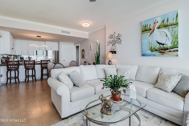 living room with a textured ceiling, visible vents, and tile patterned floors