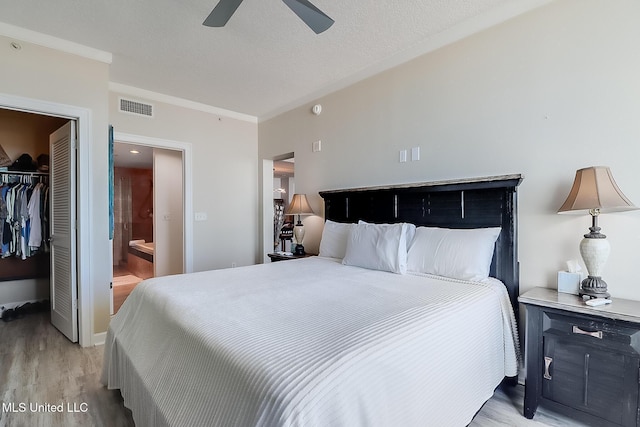 bedroom with a textured ceiling, visible vents, a spacious closet, a closet, and light wood-type flooring