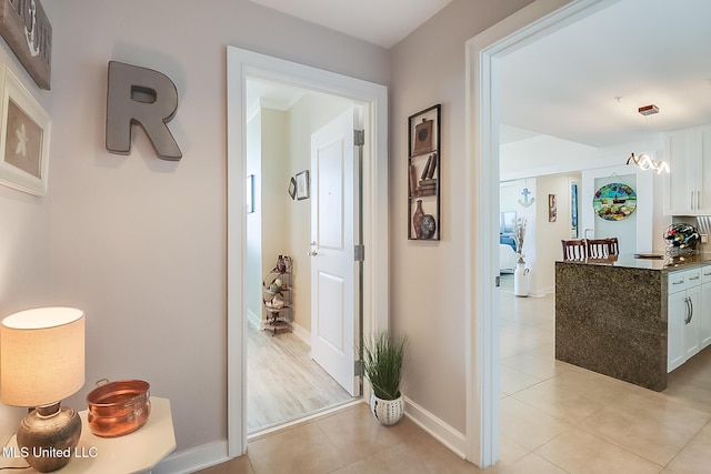 hallway with baseboards and light tile patterned flooring