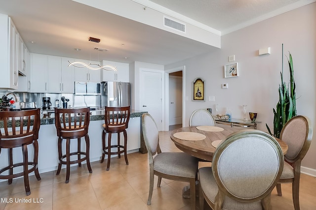 dining space with light tile patterned floors, visible vents, and ornamental molding