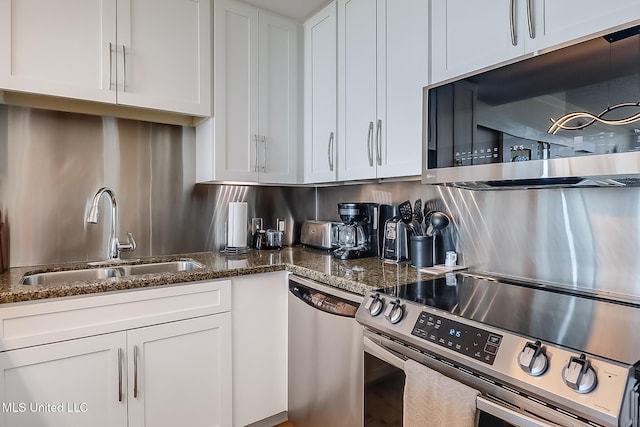 kitchen featuring dark stone counters, appliances with stainless steel finishes, a sink, and white cabinets