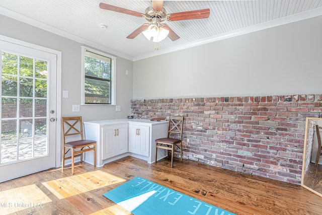 sitting room featuring a ceiling fan, brick wall, crown molding, and light wood finished floors