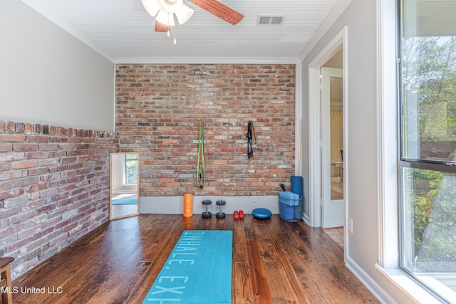 workout room with ornamental molding, visible vents, brick wall, and wood finished floors