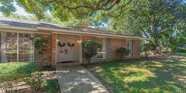 view of exterior entry with brick siding and a lawn