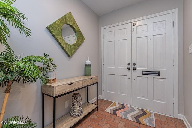 foyer entrance with brick floor and baseboards