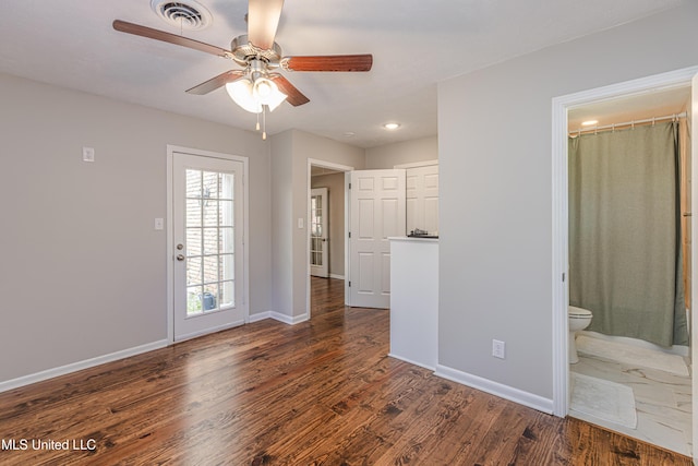 interior space featuring a ceiling fan, visible vents, baseboards, and dark wood-type flooring