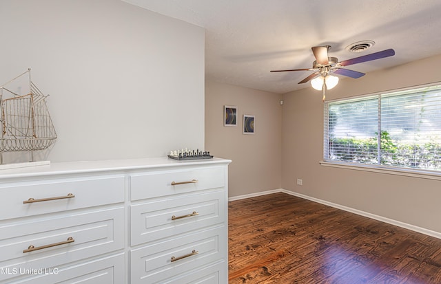 empty room featuring visible vents, dark wood finished floors, baseboards, and ceiling fan