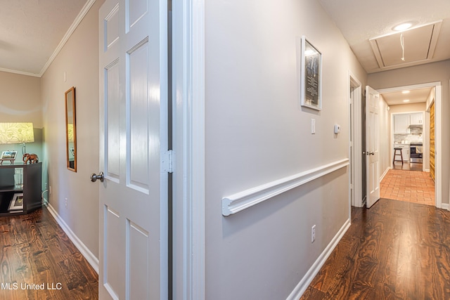 hallway with attic access, baseboards, dark wood finished floors, and ornamental molding