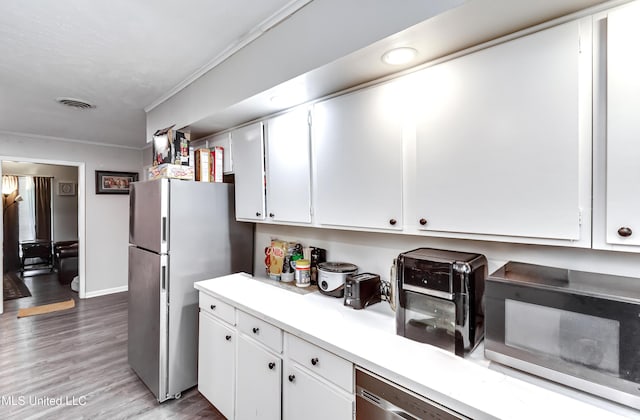 kitchen featuring light hardwood / wood-style floors, white cabinets, appliances with stainless steel finishes, and ornamental molding