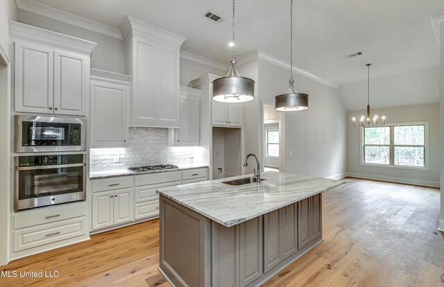 kitchen featuring sink, light stone counters, decorative light fixtures, white cabinets, and appliances with stainless steel finishes