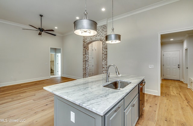 kitchen featuring a kitchen island with sink, sink, gray cabinets, light wood-type flooring, and decorative light fixtures