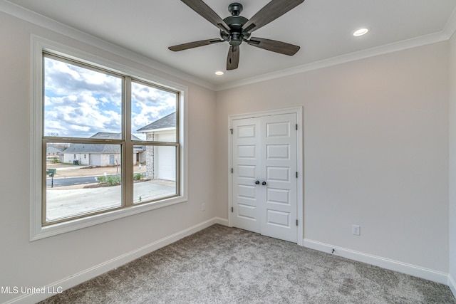 empty room featuring a wealth of natural light, crown molding, ceiling fan, and light colored carpet