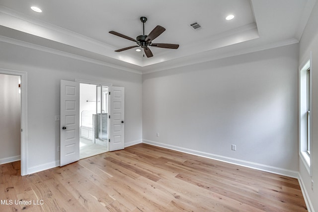 unfurnished bedroom with ceiling fan, a raised ceiling, light wood-type flooring, and crown molding