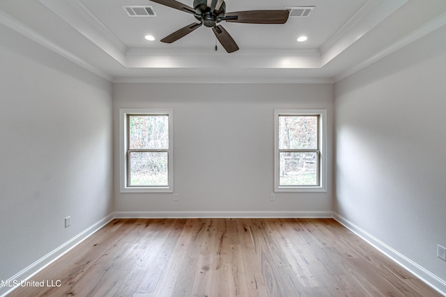 spare room with light hardwood / wood-style flooring, crown molding, and a tray ceiling