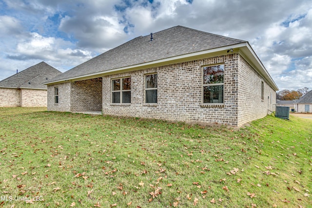 back of property featuring central air condition unit and a lawn