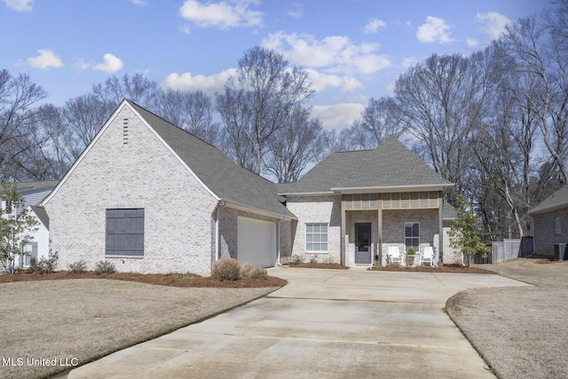 view of front facade featuring an attached garage, covered porch, a shingled roof, concrete driveway, and brick siding